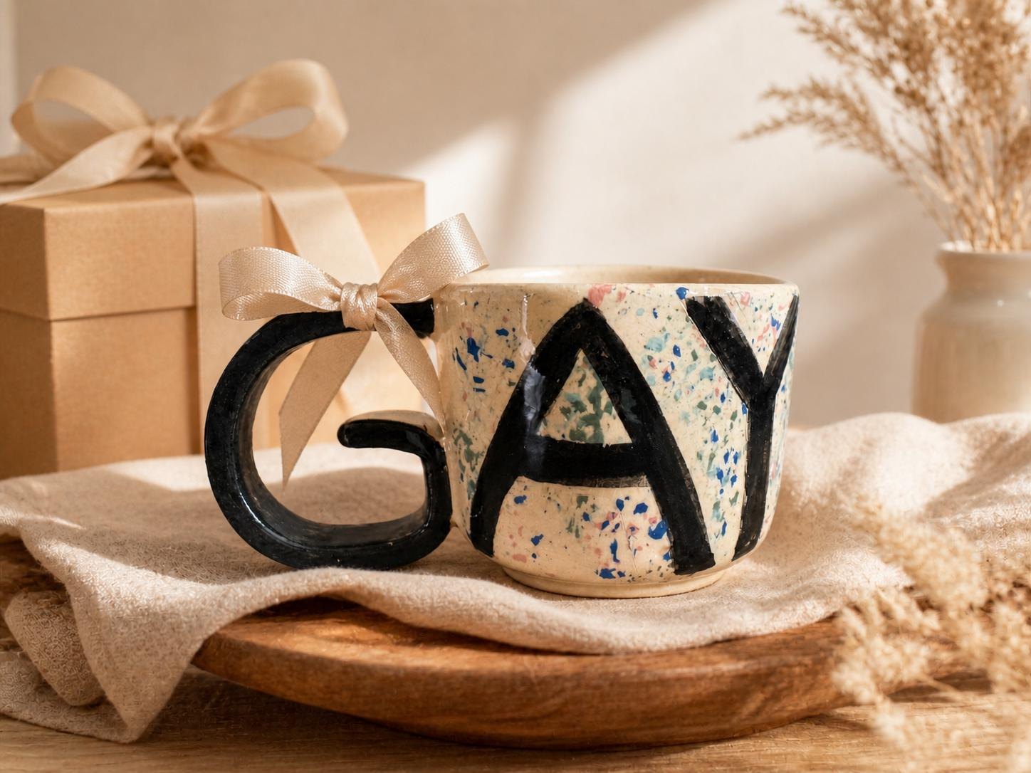 GAY Tasse als Geschenk neben einer Geschenkbox